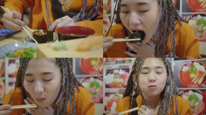 亚洲年轻女子在亚洲餐厅用筷子吃日本寿司卷