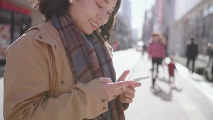 年轻女子在城市外面发短信智能手机。