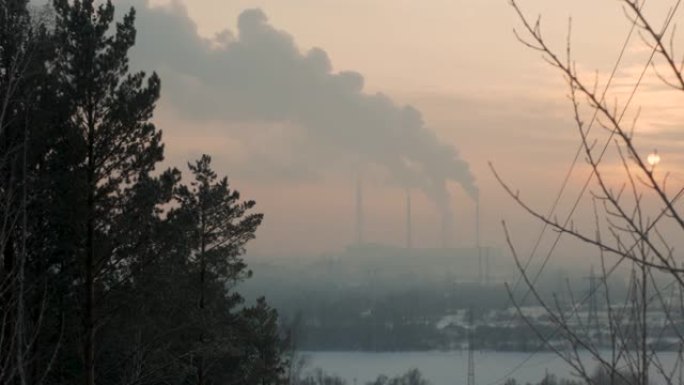 冬天雾中日落时工作的植物。从工厂烟囱冒出烟雾