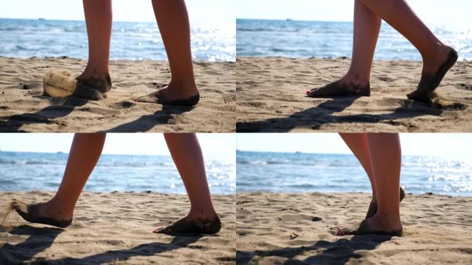 女性的脚在沙滩上的金色沙滩上行走，背景是海景。年轻女子沿着海边行走的腿。赤脚女孩在海洋海岸附近漫步。