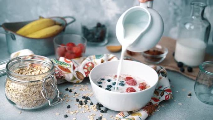 早餐碗配新鲜蓝莓、草莓和牛奶: 倒牛奶