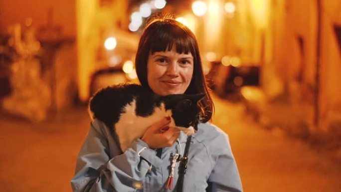 猫。女孩在夜市的背景下抚摸一只猫。意大利。
