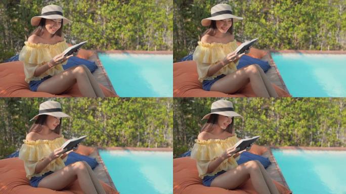 年轻的亚洲女性在室外游泳池附近看书