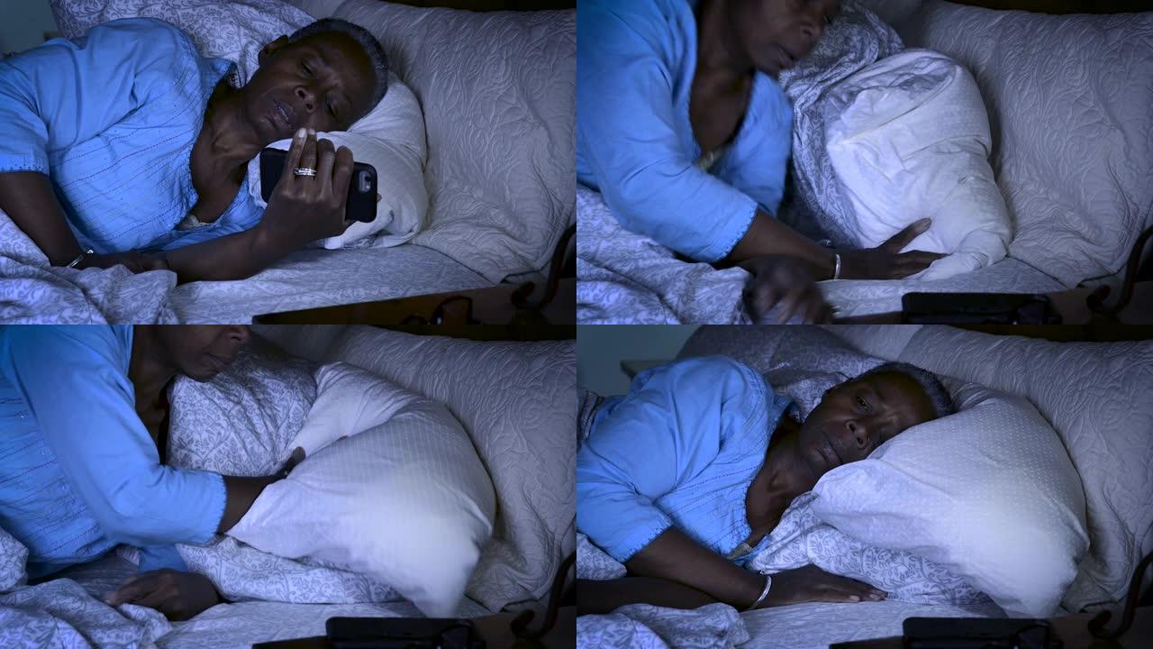 资深黑人妇女晚上躺在床上清醒检查手机