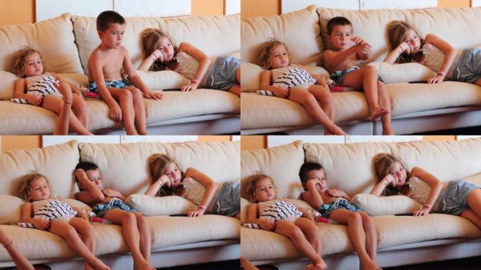家里的孩子坐在客厅沙发上，孩子们盯着电视屏幕看电影