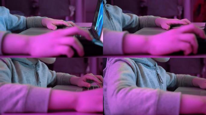 男孩点击鼠标并在键盘上打字。玩电子游戏和使用电脑的孩子。未来的rgb背光