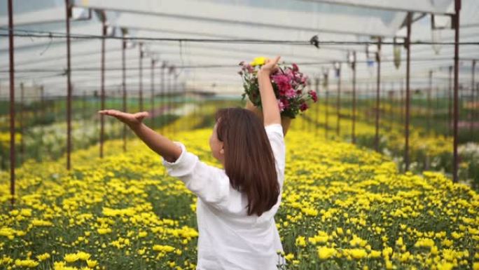 亚洲成熟女人在菊花花场的面部表情，展示花篮和姿势自由，双臂伸出