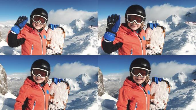 微笑的孩子在雪山上滑雪和挥手