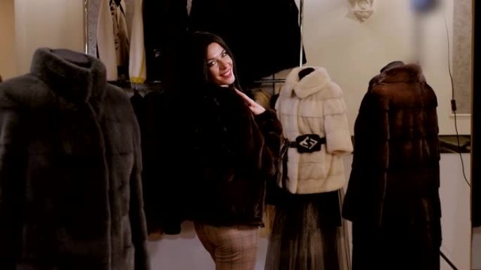 一个长发的豪华女孩在一家女装商店试穿皮大衣。