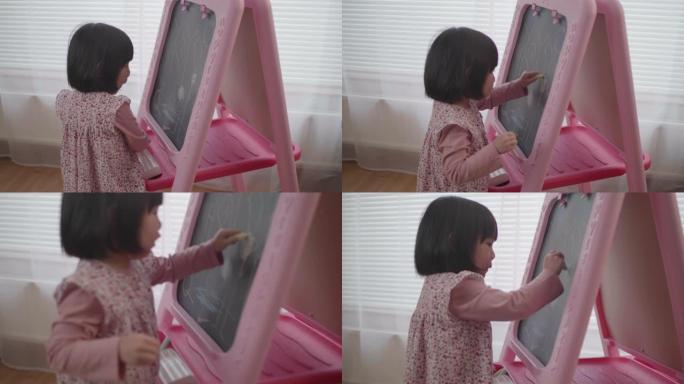 蹒跚学步的女孩在家里的黑板上画画