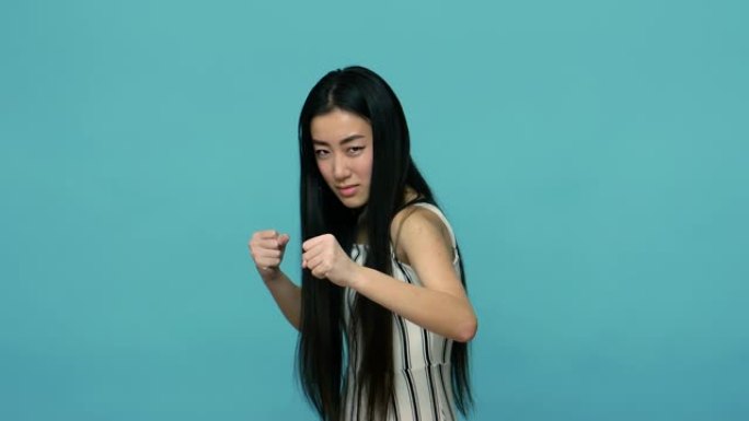 让我们战斗吧!咄咄逼人的亚洲女性，穿着黑色长发，准备用紧握的拳头拳击