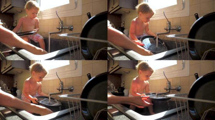 妈妈洗碗时，孩子坐在水槽里。母女概念。厨房职责。家务和孩子。正在工作的母亲和蹒跚学步的孩子。母亲的手
