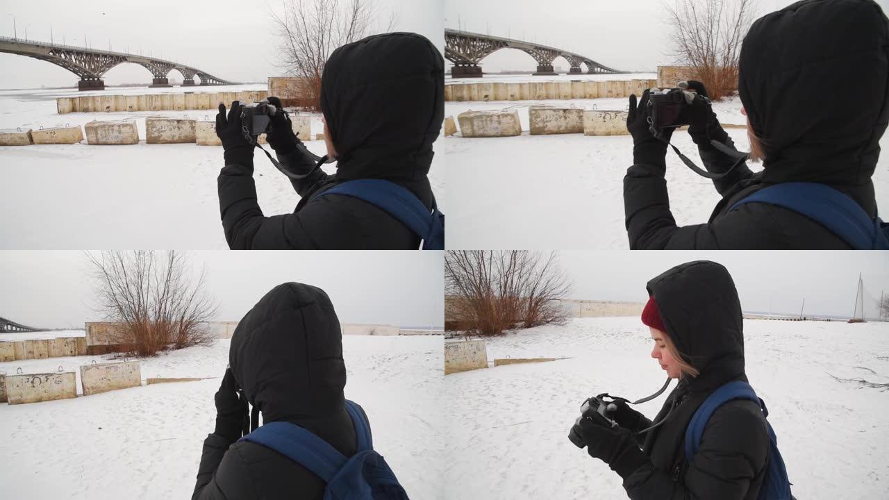 一个女孩在河边拍摄冬天的风景。女摄影师在城市的桥上拍照。