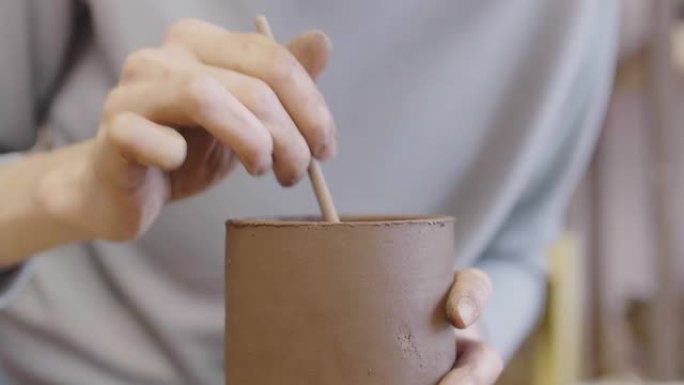 陶艺家在粘土马克杯中混合涂料