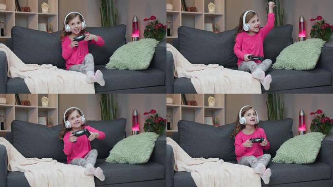 小女孩坐在沙发上在家里的客厅里播放视频。兴奋的玩家女孩手握操纵杆用无线控制器玩游戏机游戏。玩得开心，
