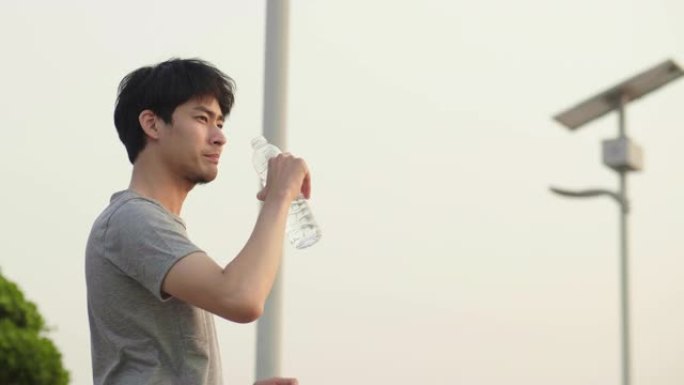 亚洲男子运动员在城市跑步后饮水