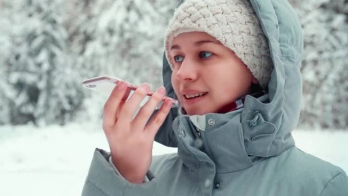 微笑的旅游女孩在户外用手机发送语音信息，语音识别ai，冬季森林的学生模型