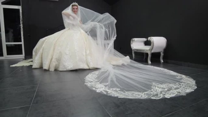 年轻漂亮的新娘穿着白色婚纱玩面纱把它推向