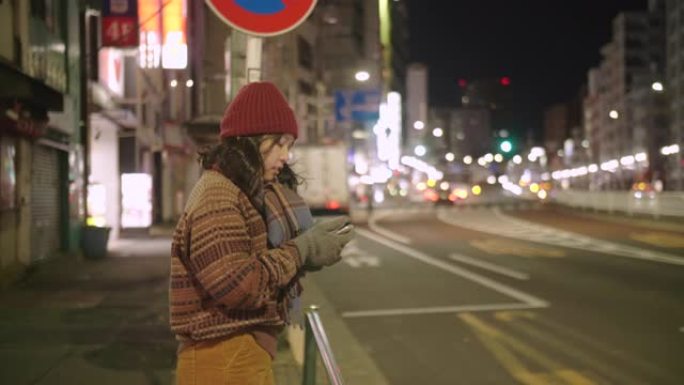 在东京市，亚洲女孩戴上羊毛帽子和围巾等出租车。