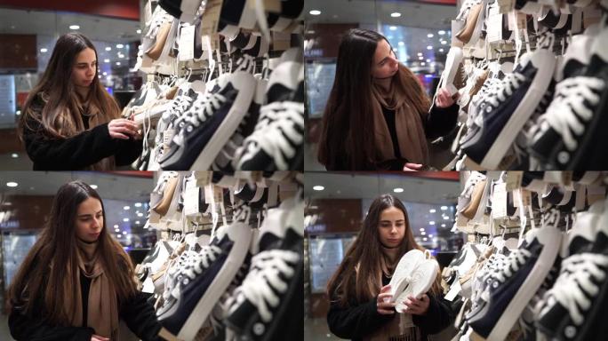 鞋店里的一名年轻女子选择运动鞋。一个女人在精品店买鞋。女性选择鞋子。概念: 在服装店购物和购物