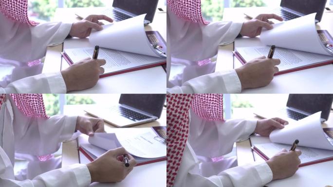 宽镜头阿拉伯男子审查并签署文件