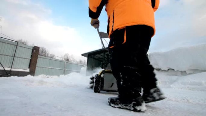 男子在冬天用扫地机清理院子里的雪