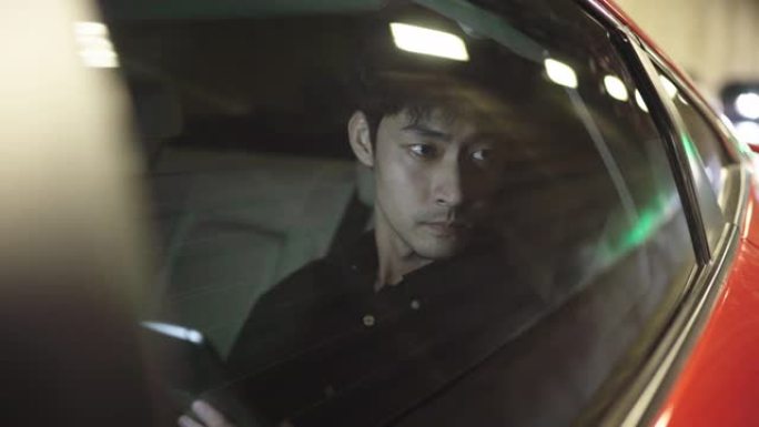 年轻的亚洲男子在出租车中使用智能手机/夜间Uber