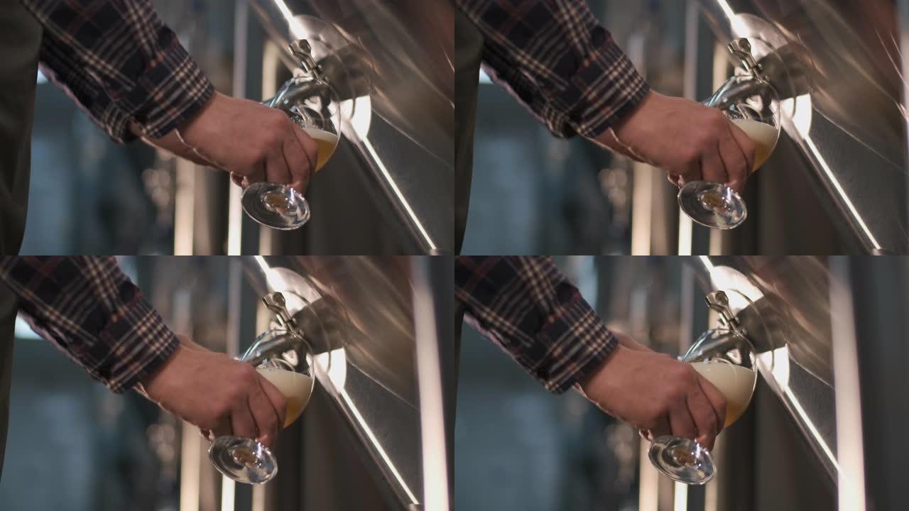 一位男性酿酒师将啤酒从啤酒罐中倒入玻璃杯中品尝。特写
