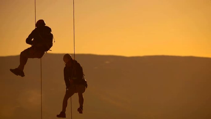 夫妻在绳子上用智能手机拍照。日落登顶登山队