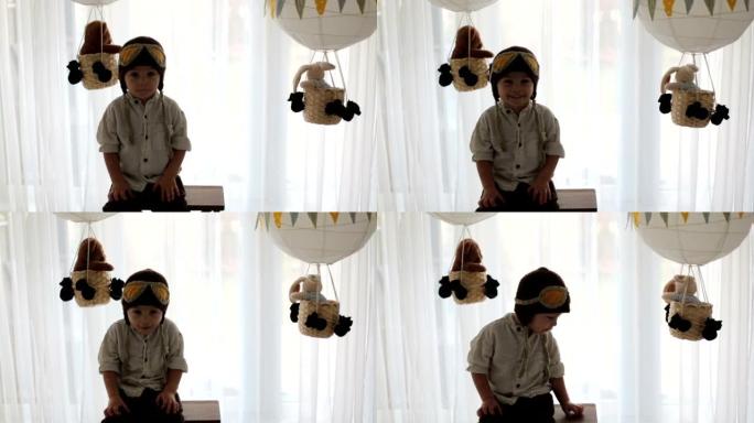 可爱的蹒跚学步的男孩，玩着飞机和泰迪熊，身后装有玩具的气球