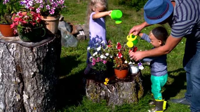 父亲教孩子如何在花园里浇花。女儿和儿子