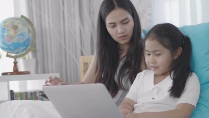 亚洲女孩和姐妹正在使用笔记本电脑，计算机和平板电脑连接到网络世界。小女孩在家休息时使用互联网。