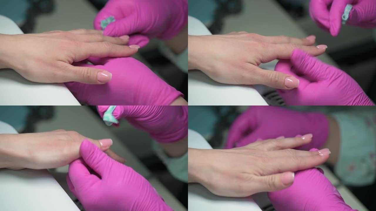 修指甲美容师的特写镜头用纸巾擦拭客户的抛光指甲
