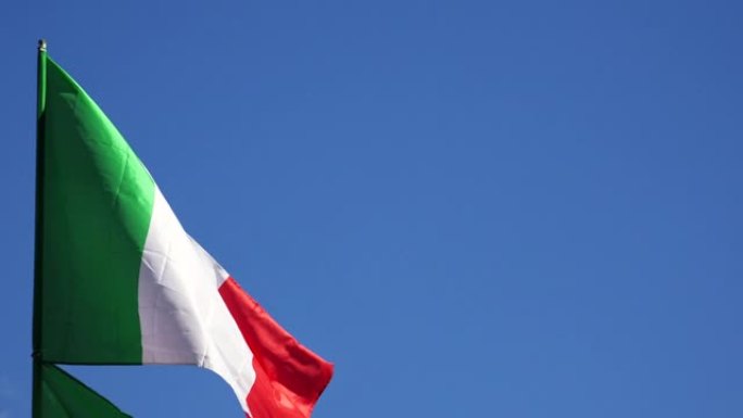 天空和飞舞的云朵背景上的意大利国旗。4 k。