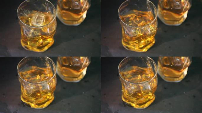 黑色桌子上的两杯威士忌加冰。冰落在玻璃杯中