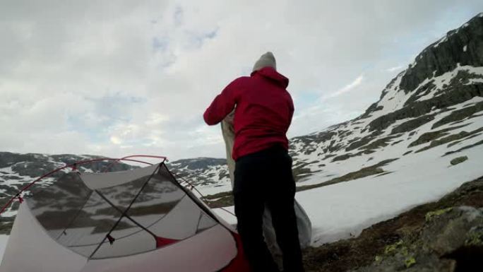 一对年轻夫妇在挪威特罗尔通加附近搭起帐篷。大自然中的野外露营。夫妻玩得很开心。他们被雪包围着。冬季登