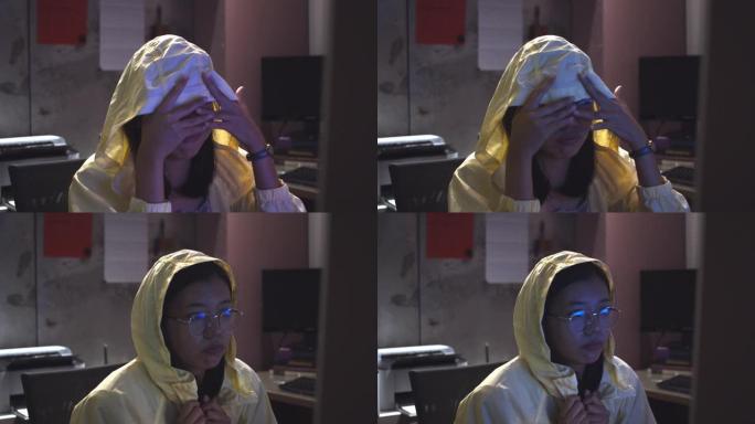 亚洲美女在办公室背景下晚上在电脑屏幕上观看恐怖电影，眼镜反射。加班到深夜的概念。