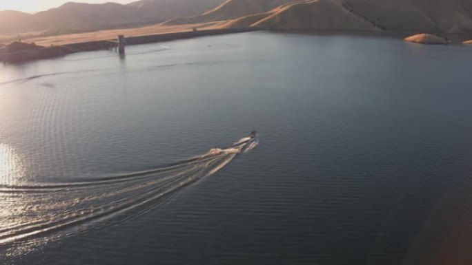 空中无人机跟踪拍摄了一艘有两个滑水者的船。一个山湖 (加利福尼亚州维萨利亚的卡维阿湖)