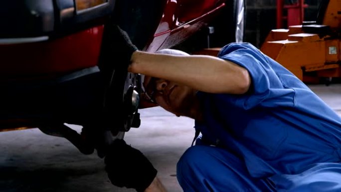 汽车修理工检查汽车车库的制动盘。