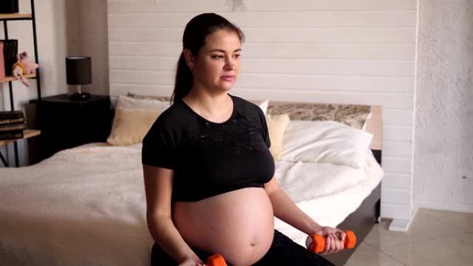 Pregnant woman goes in for sports with dumbbells s