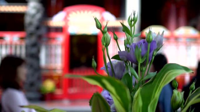 亚洲寺庙祭祀用的花。模糊的背景是崇拜者。主题在右边。