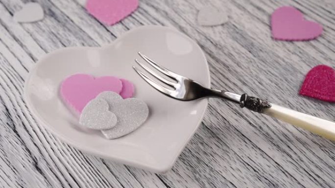 装饰心落在带有甜点叉的心形盘子上。在木制轻纹理桌上