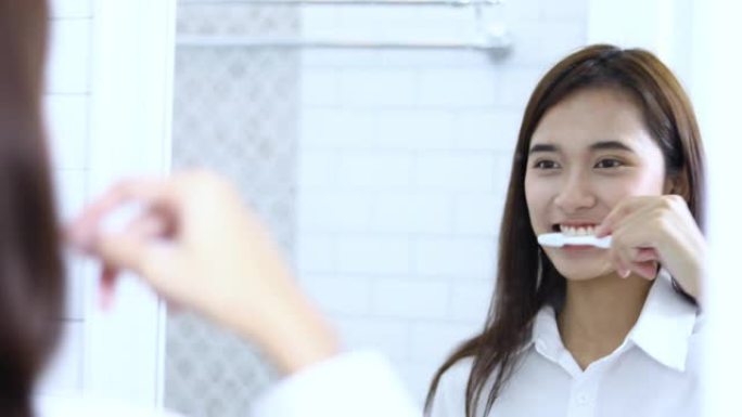 亚洲女性早上在浴室挤牙膏刷牙。