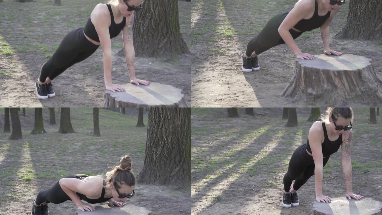 在公园的木头上做俯卧撑，适合在树林里锻炼的女人。在露天天然健身房锻炼。俯卧撑。有吸引力的女运动员锻炼