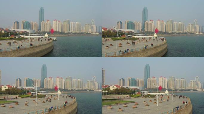 阳光明媚的日落青岛市著名的步行湾码头广场空中全景4k中国