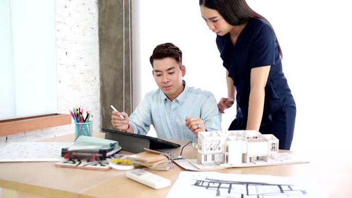 亚洲室内建筑师与建筑模型一起工作，选择材料并研究大众模型房屋设计思想概念。设计师小组头脑风暴在新房子