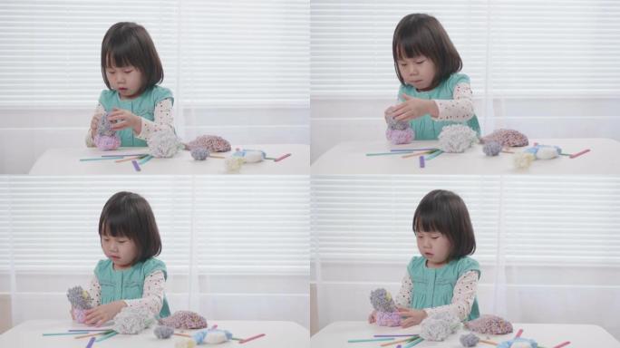蹒跚学步的女孩在白色窗户背景下在桌子上玩泡沫