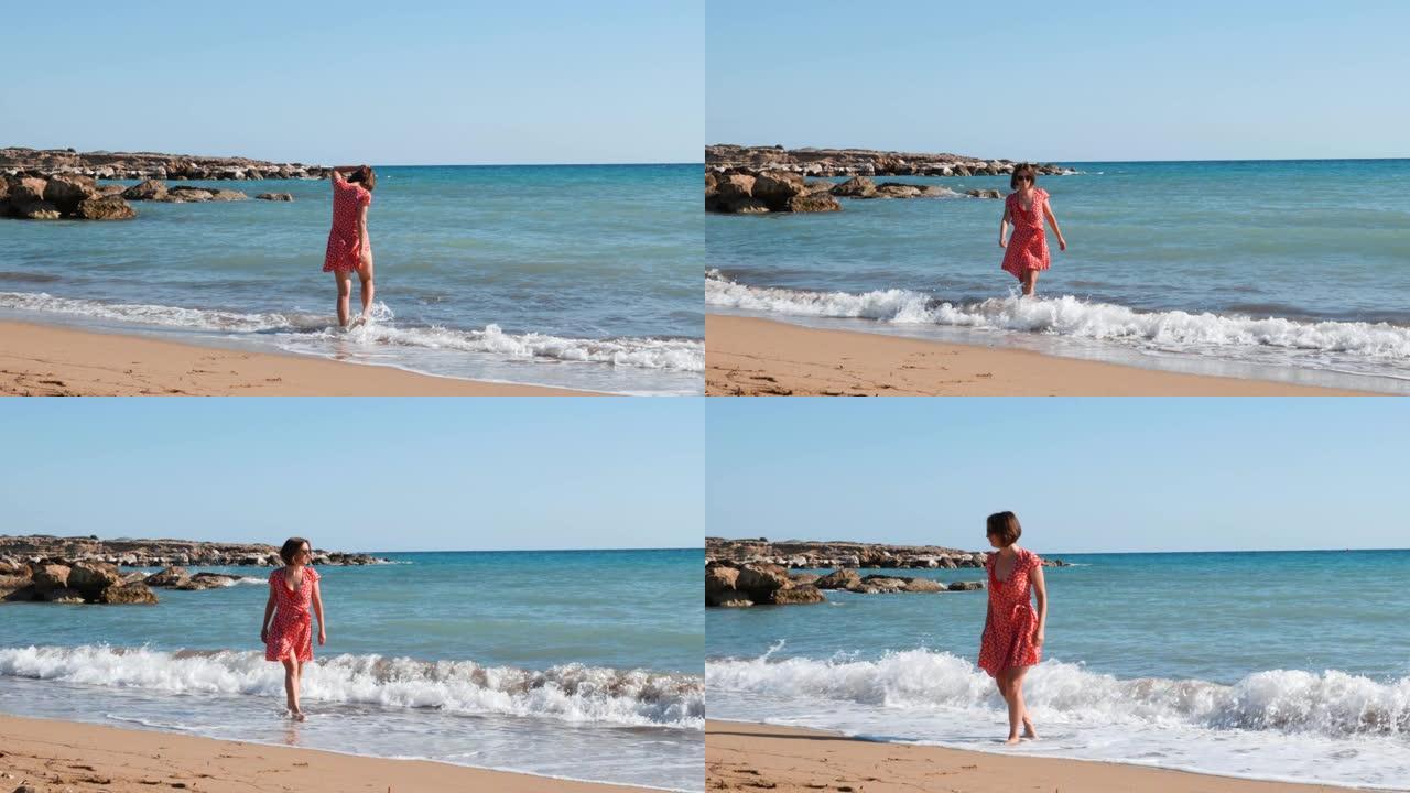 年轻迷人的女孩沿着沙滩散步。黑发女孩在海边玩得开心。女孩在海边晒太阳。女孩在海水附近的海滩上放松。女