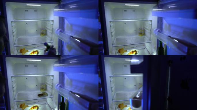 在冰箱里找食物的人。一名男子将啤酒和未食用的罐头放入冰箱。