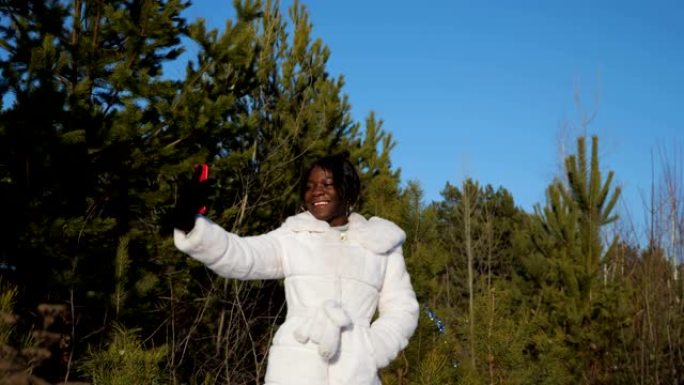 黑人妇女在晴朗的天空下在冬季森林中自拍